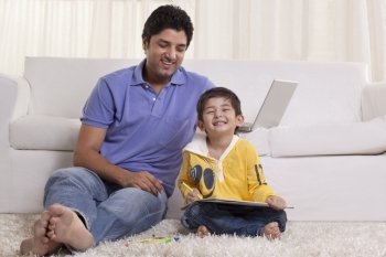 Smiling father assisting his son in drawing at home 