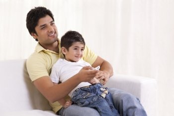 Smiling father and son watching television 