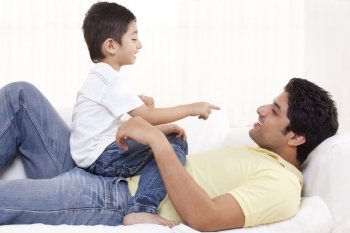 Cute boy sitting on father at home 