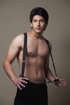 Portrait of shirtless man wearing suspenders 