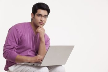 Young man thinking while using laptop 