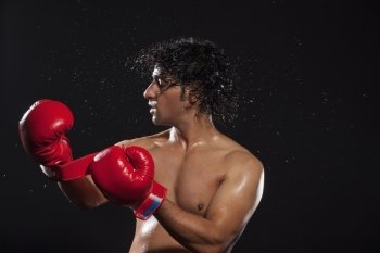 Young man tossing hair while wearing boxing gloves 