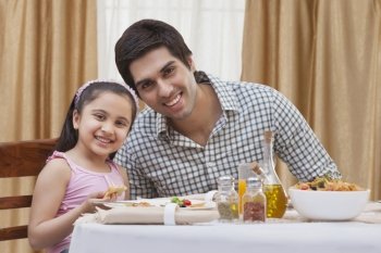Portrait of a happy father and daughter having pizza at restaurant 