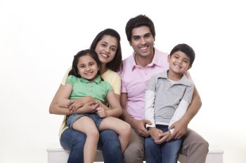Portrait of a happy family sitting on bench over white background 