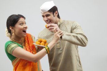Maharashtrian man trying to feed woman a laddoo