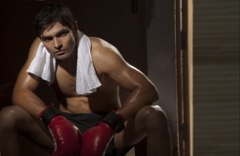 Tired young male boxer looking away in gym