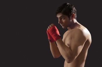 Side view of young male boxer practicing isolated over black background