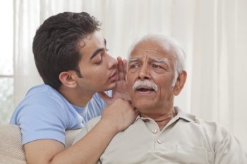 Grandson whispering into grandfather’s ear