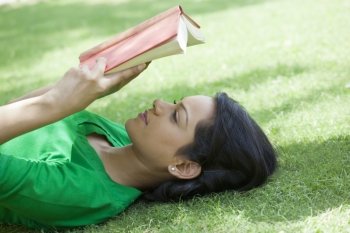 Woman lying on grass reading a book