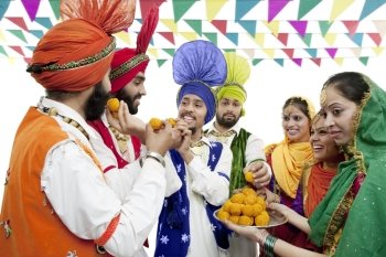 Sikh people eating laddoos 