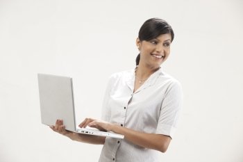 Happy young woman smiling while using laptop 
