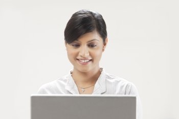 Smiling young businesswoman using laptop on white background 