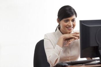 Smiling young businesswoman looking at computer 
