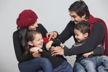 Happy playful family sitting over grey background 