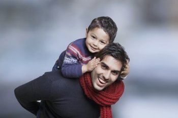 Father giving boy piggy back ride outdoors 
