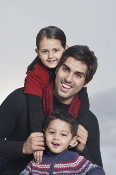 Portrait of happy father with children over grey background 