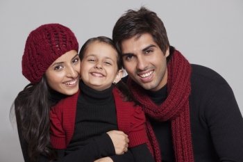 Smiling parents with their daughter over grey background 