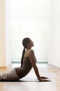 Young woman doing yogic ’sun salutation’ on mat