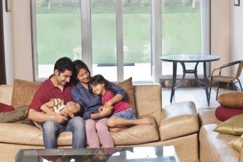 Parents sitting together with kids on sofa at home 