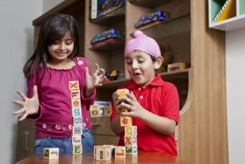 Siblings playing with wooden toy blocks 