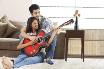 Relaxed young couple playing guitar together at home 