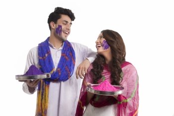 Couple holding thalis with holi colour