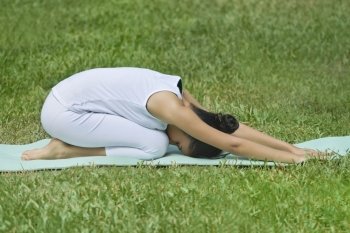 Young woman doing yoga on a lawn 