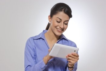 Happy businesswoman using tablet computer over gray background