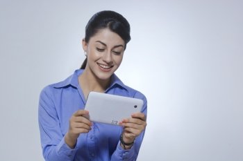 Happy businesswoman using tablet PC over gray background