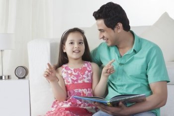 Cute girl explaining story to father on sofa at home