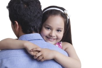 Portrait of happy girl embracing father against white background