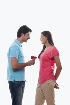 Young man giving rose to woman over white background