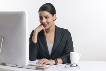 Young businesswoman using computer at desk against white background