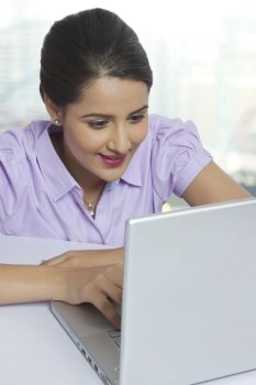 Young businesswoman using laptop at office desk
