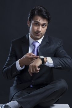 Young businessman checking time against black background