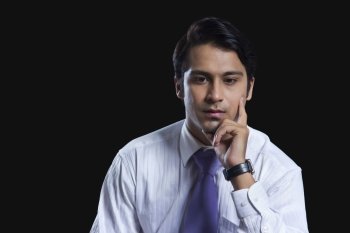 Thoughtful businessman with hand on chin over black background