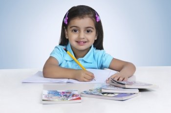Portrait of cute girl studying against blue background