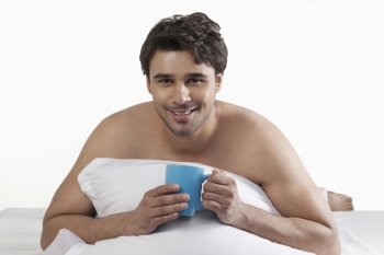 Man with a cup of coffee in bed 