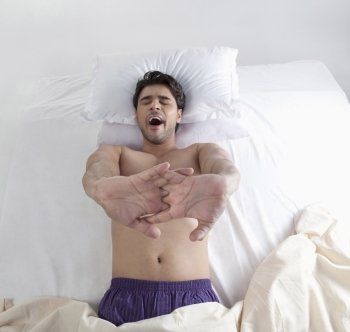 Man stretching his arms in bed 