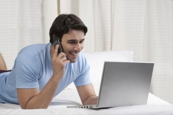 Man talking on the phone while working on a laptop 