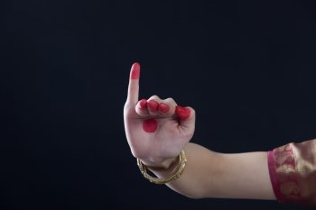 Close-up of a woman’s hand making Bharatanatyam gesture called Hamsapaksha on black background