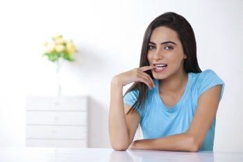Portrait of beautiful young woman with finger in mouth at home