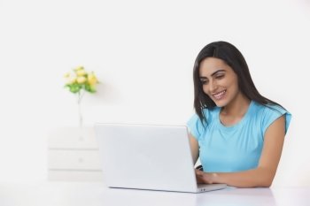 Happy young woman using laptop at home