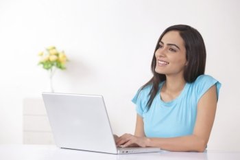 Thoughtful young woman using laptop at home
