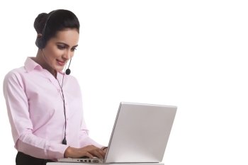 Indian businesswoman using headset and laptop against white background