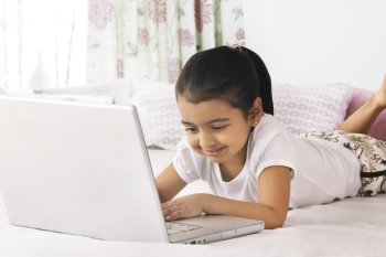 Cute girl using laptop in bed
