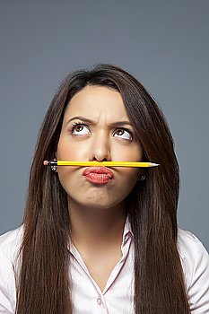 Female executive balancing pencil on lip