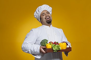 Portrait of chef with tray of vegetables