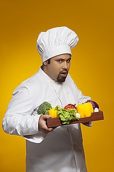 Portrait of chef with tray of vegetables