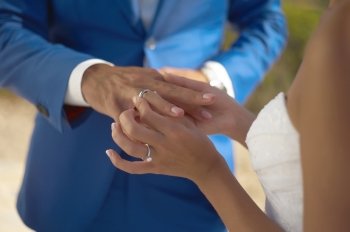 The bride wears a wedding ring on the groom. Closeup photo